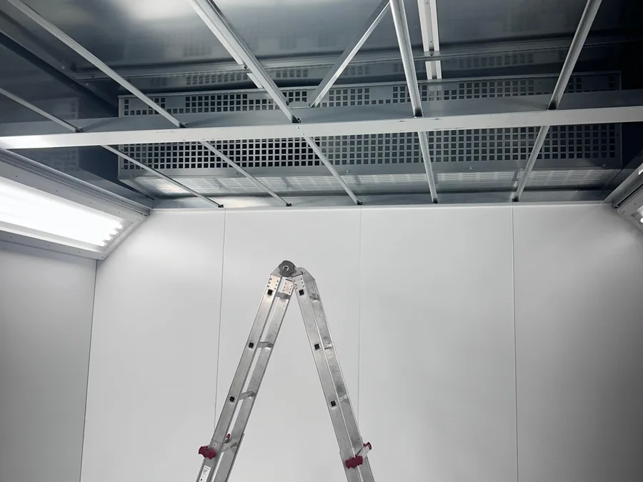 Innenansicht der Lackierkabine: Filterdecke mit Leuchtbändern, Gitterrostboden und eine Leiter in der Kabine
